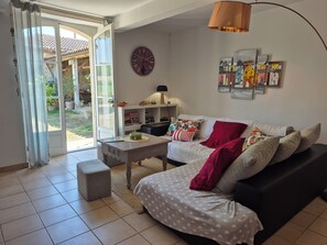 Una sala de estar con un sofá, una mesita de centro y una estantería. Hay una puerta que da a un balcón.
