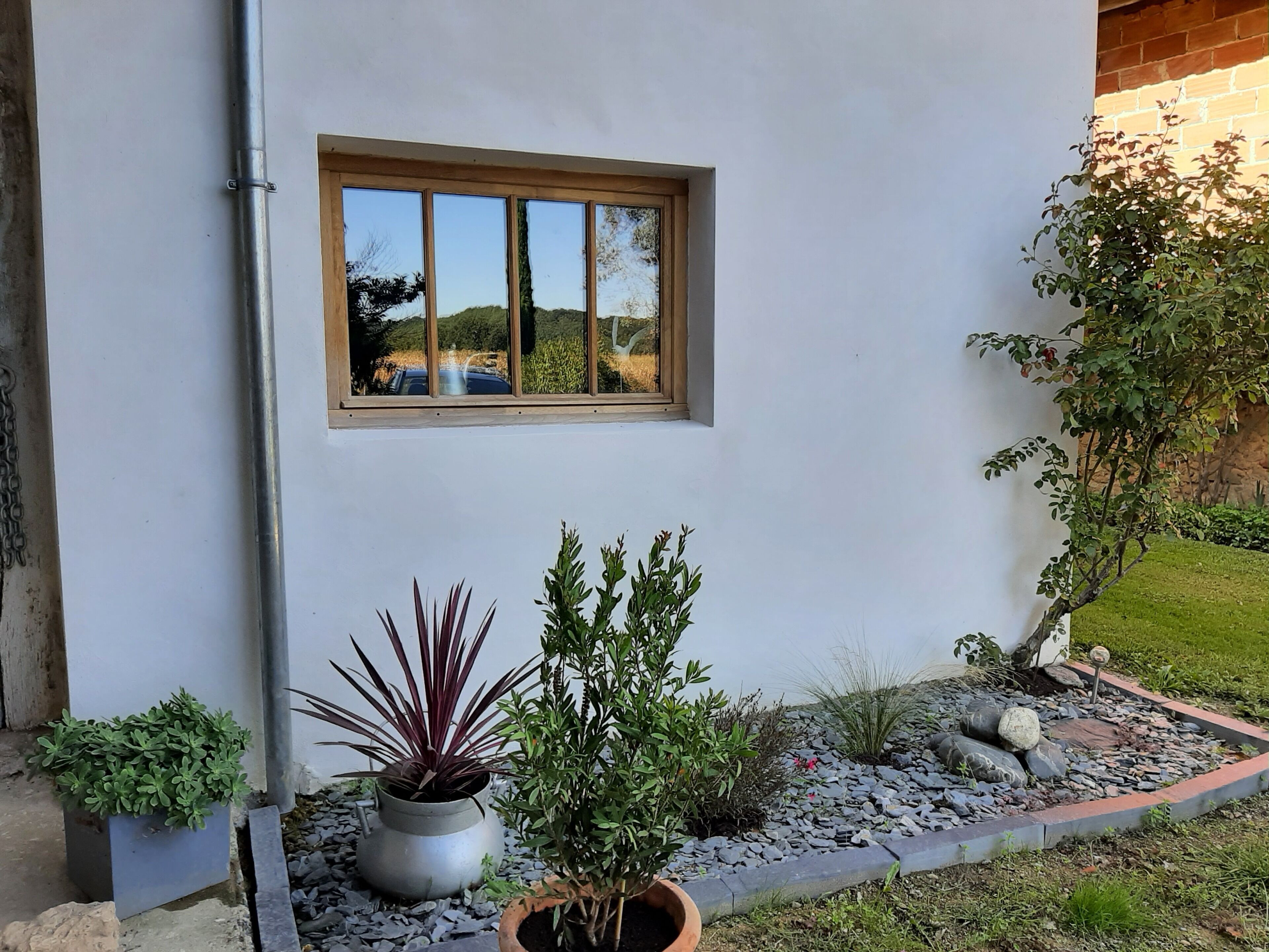 A white building with a window reflecting a landscape, potted plants, and a stone pathway. - Children's paradise calm nights, guest animals, plenty of Playmobilss (Troncens)