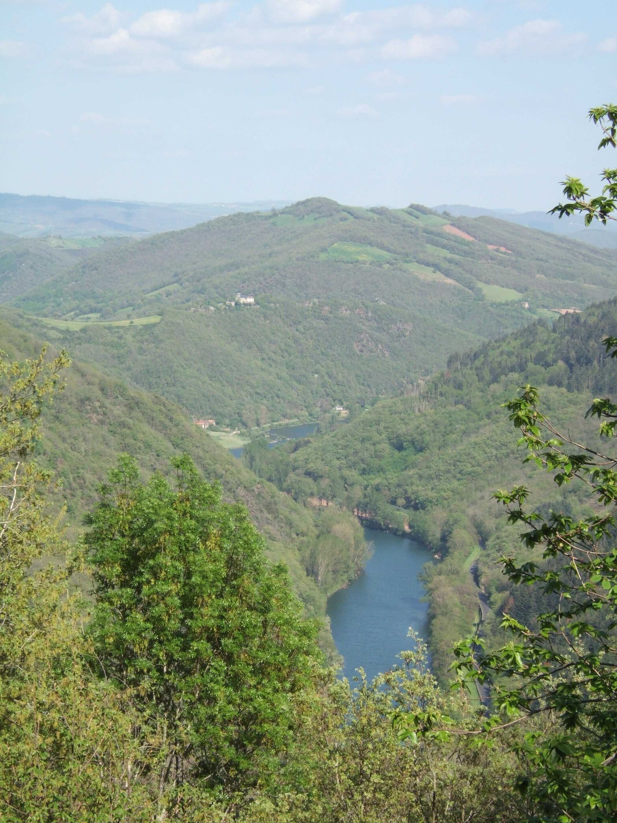 Un valle con un río, rodeado de colinas y edificios dispersos.