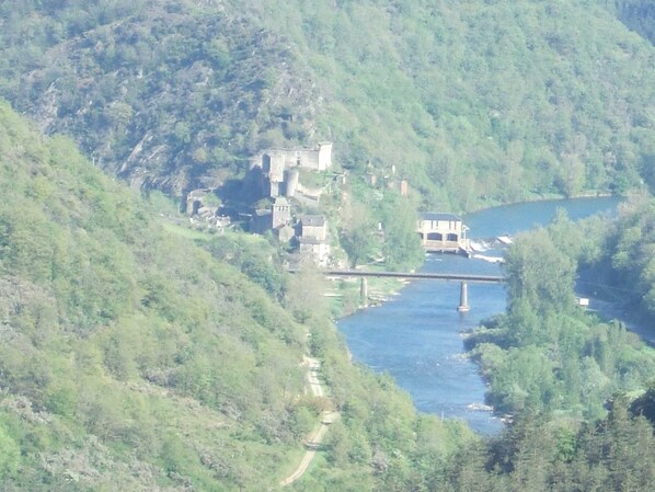A castle-like structure surrounded by lush greenery and a river.