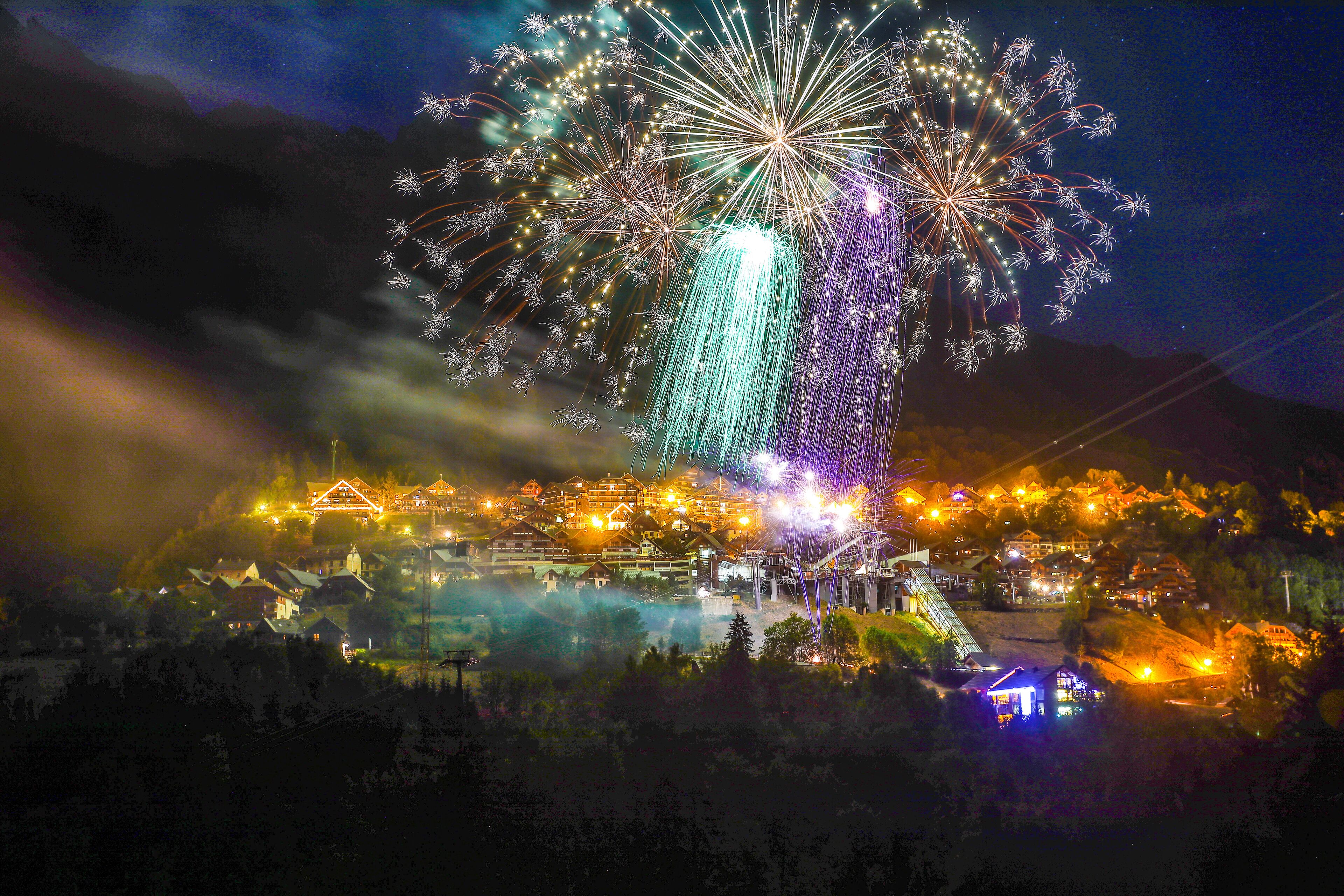 A nighttime view of a resort with illuminated buildings and a large display of fireworks.