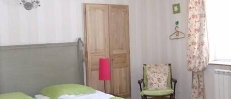 Una habitación con cama, silla, armario y radiador.