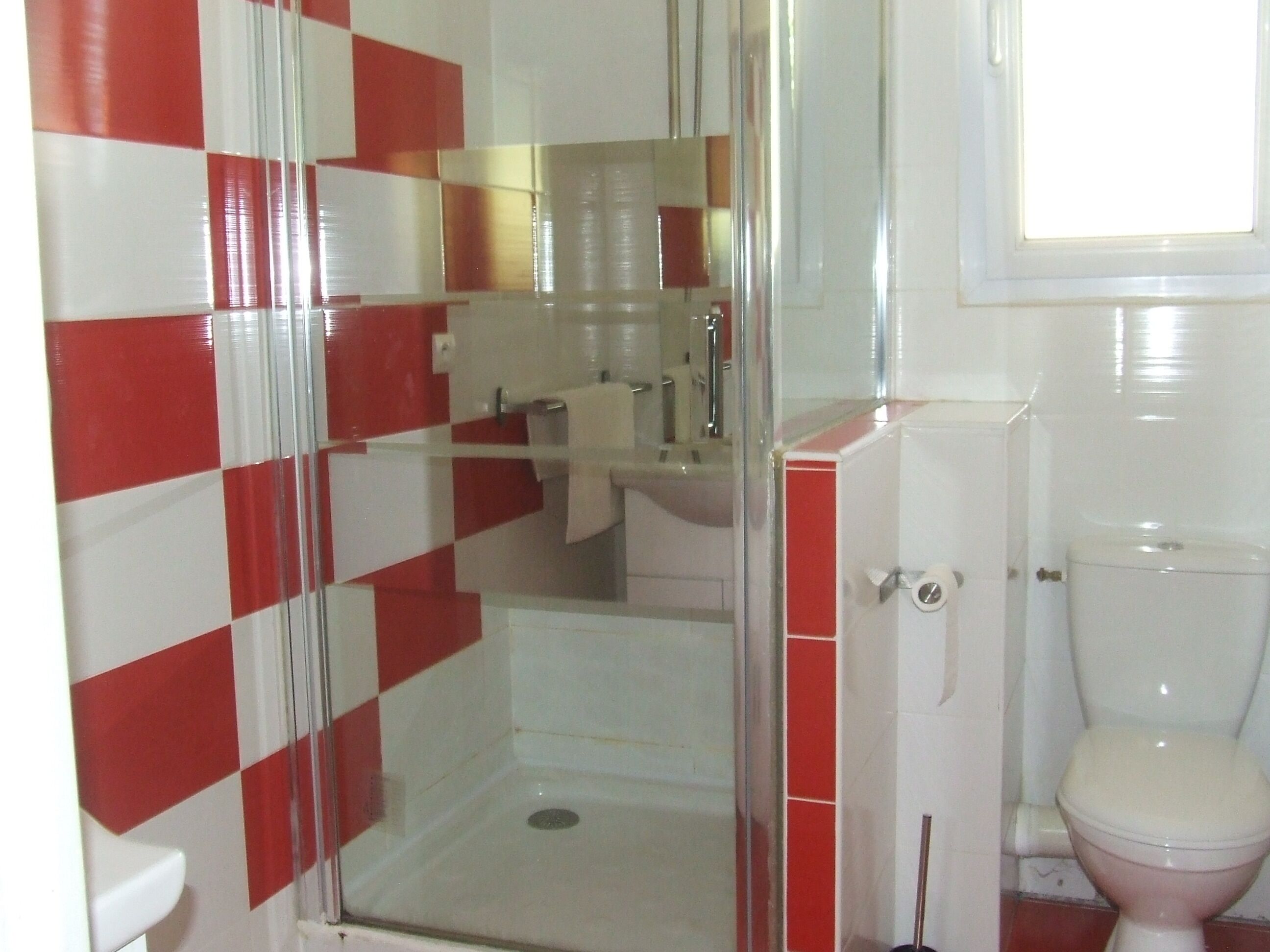 Une salle de bain avec une douche à parois de verre, des toilettes et un lavabo.