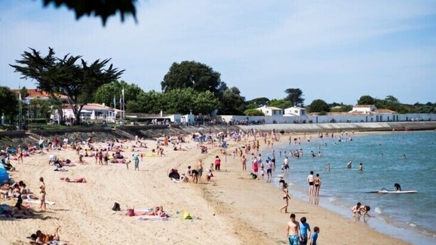 Ein voller Strand mit Menschen, die sich sonnen und schwimmen.