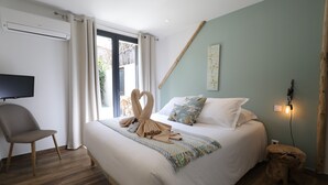 Un dormitorio con cama, una silla, un televisor y una ventana con cortinas.