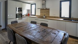 Una cocina moderna con armarios blancos, una mesa de comedor de madera y un horno empotrado.
