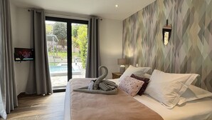 Una habitación de hotel moderna con una cama grande, televisión y vistas a una piscina.