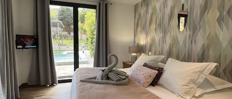 Een moderne hotelkamer met een groot bed, een televisie en uitzicht op een zwembad.