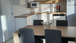 Eine moderne Küche mit weißen Schränken, einer Mikrowelle, einer Kaffeemaschine und einem Essbereich mit Tisch und Stühlen.