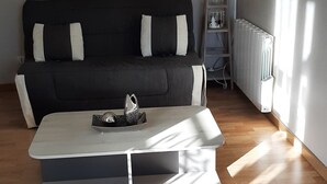 Ein Wohnzimmer mit einer schwarzen Couch, einem weißen Couchtisch und einer Heizung.