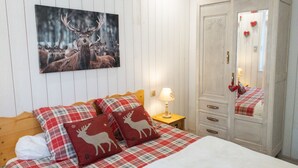 Un dormitorio con cama, mesita de noche, cómoda, espejo y un cuadro de un ciervo.