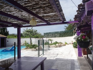 Une terrasse couverte avec une piscine, une table et un luminaire suspendu.