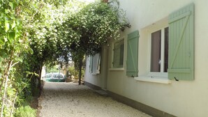 A narrow gravel path leading to a building with green shutters and a white wall. - Gîte La Salsepareille 6-person house near Pézenas with garden and air conditioning (Caux)