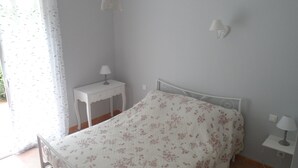 A bedroom with a bed, a nightstand, a lamp, and a wall-mounted light fixture. - Gîte La Salsepareille 6-person house near Pézenas with garden and air conditioning (Caux)