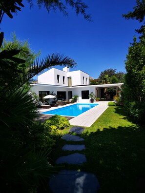 A modern house with a swimming pool, surrounded by lush greenery and a clear blue sky. - beautiful modern villa with heated pool near: sea, golf, tennis and shops (Anglet)