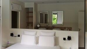 A modern hotel room with a large bed, a small round table, and a bathroom visible through an open door. - beautiful modern villa with heated pool near: sea, golf, tennis and shops (Anglet)