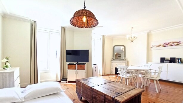 A modern hotel room with a wooden bed, a dining table with chairs, a TV, and a kitchen area. - Provencal Style and Large 1 Bedroom Rue Florian (Cannes)