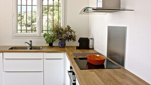A modern kitchen with a stainless steel sink, a window with bars, a potted plant, a toaster, and a refrigerator. - Sumptuous villa, comfortable, close to all amenities and beaches (Rayol-Canadel-Sur-Mer)