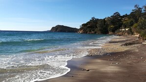 A beach with clear blue water, pebbly shore, and a rocky outcrop in the distance. - Sumptuous villa, comfortable, close to all amenities and beaches (Rayol-Canadel-Sur-Mer)
