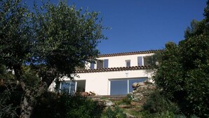 A two-story building with a white facade and brown roof tiles, surrounded by lush greenery and trees. - Sumptuous villa, comfortable, close to all amenities and beaches (Rayol-Canadel-Sur-Mer)