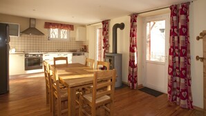 A compact kitchen with a dining area, featuring a wooden table and chairs, a built-in oven, and a chimney.