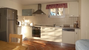 A kitchen with white cabinets, a stainless steel refrigerator, a stove, and a dishwasher.