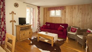 A cozy living room with a red sofa, a wooden coffee table, and a television on a wooden cabinet.
