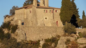 A stone building with a bell tower, arched windows, and a cross on top. - HOUSE RENTAL IN CASTELJAU (Berrias-et-Casteljau)
