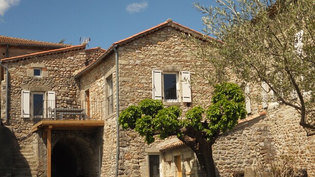 A stone building with a balcony and a small garden area. - HOUSE RENTAL IN CASTELJAU (Berrias-et-Casteljau)