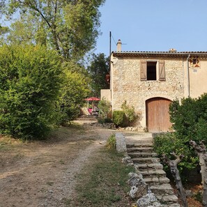 Un bâtiment rustique en pierre, avec une porte en bois et un parapluie rouge en arrière-plan.