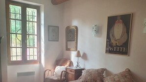 Ein Schlafzimmer mit einem großen Bett, einem Sessel, einem Tisch und einem Fenster.