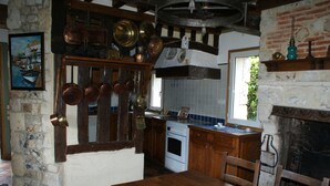 Una cocina rústica con pared de piedra, armarios de madera y un colgador para ollas.