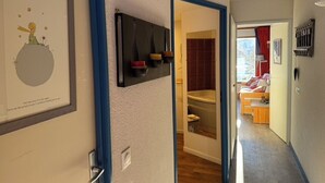 Käytävällä on seinällä kehystetty taulu, naulakko, kylpyamme ja taustalla näkyy sänky.