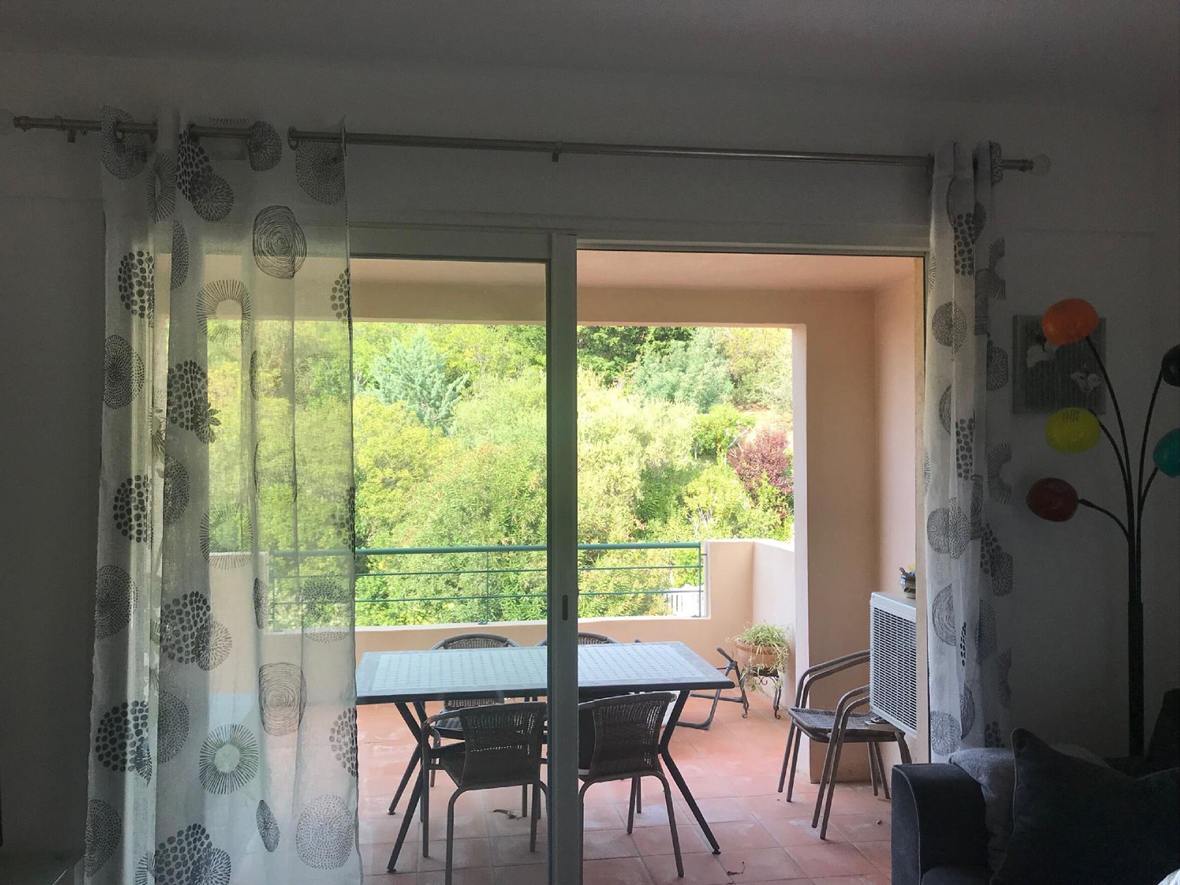 Un balcone con tavolo e sedie, una pianta in vaso e un termosifone.