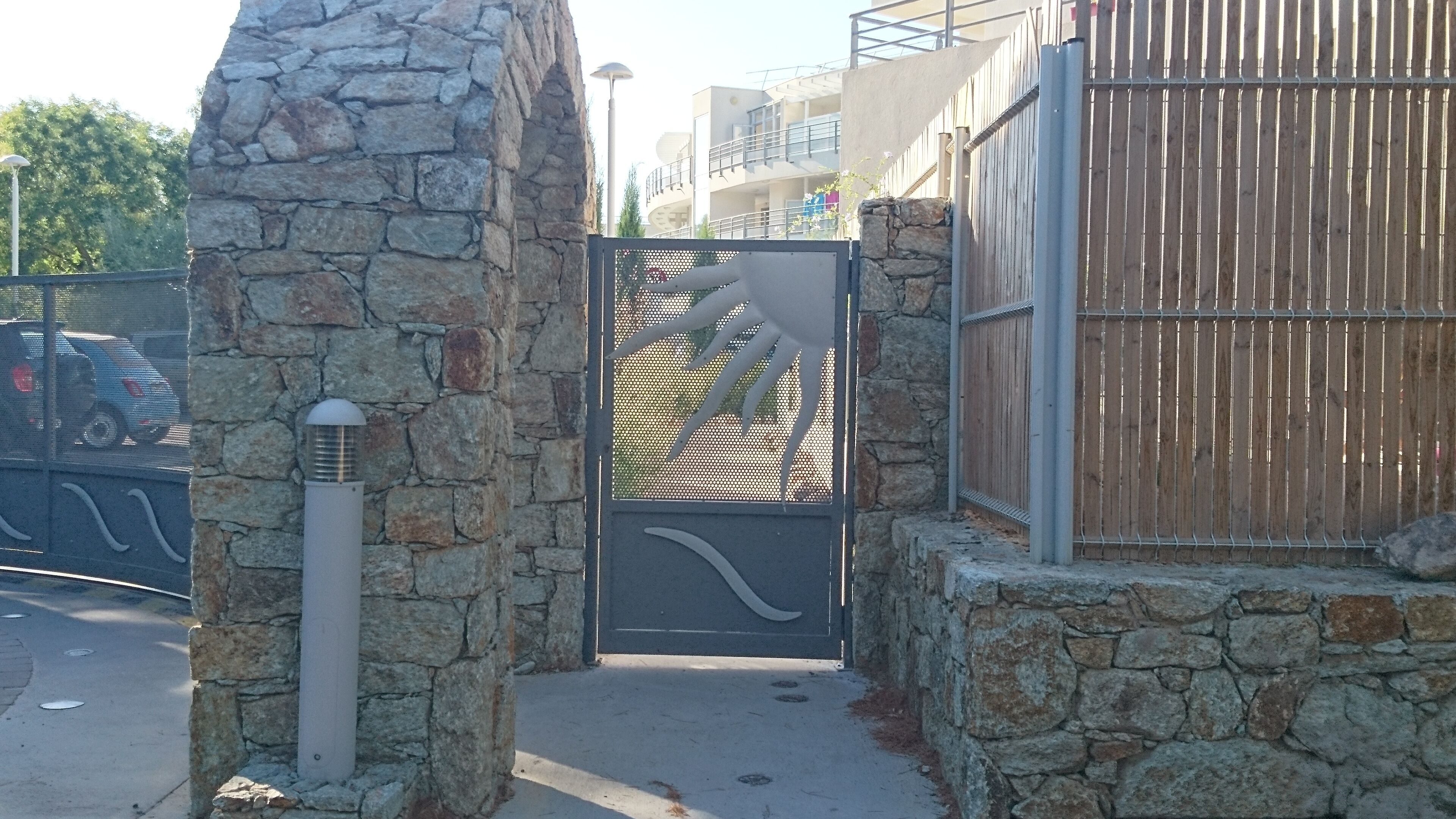 A stone gate with a metal fence and a decorative metal panel.