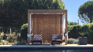 A poolside area with two lounge chairs and a wooden pergola with curtains. - CHARMING GITE IN PROVENCE IN THE HEART OF THE VINES (Sarrians)