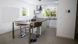 A modern kitchen with a central island, bar stools, and a window providing natural light.