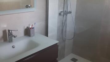 Een bad/douchecombinatie, een haardroger, handdoeken