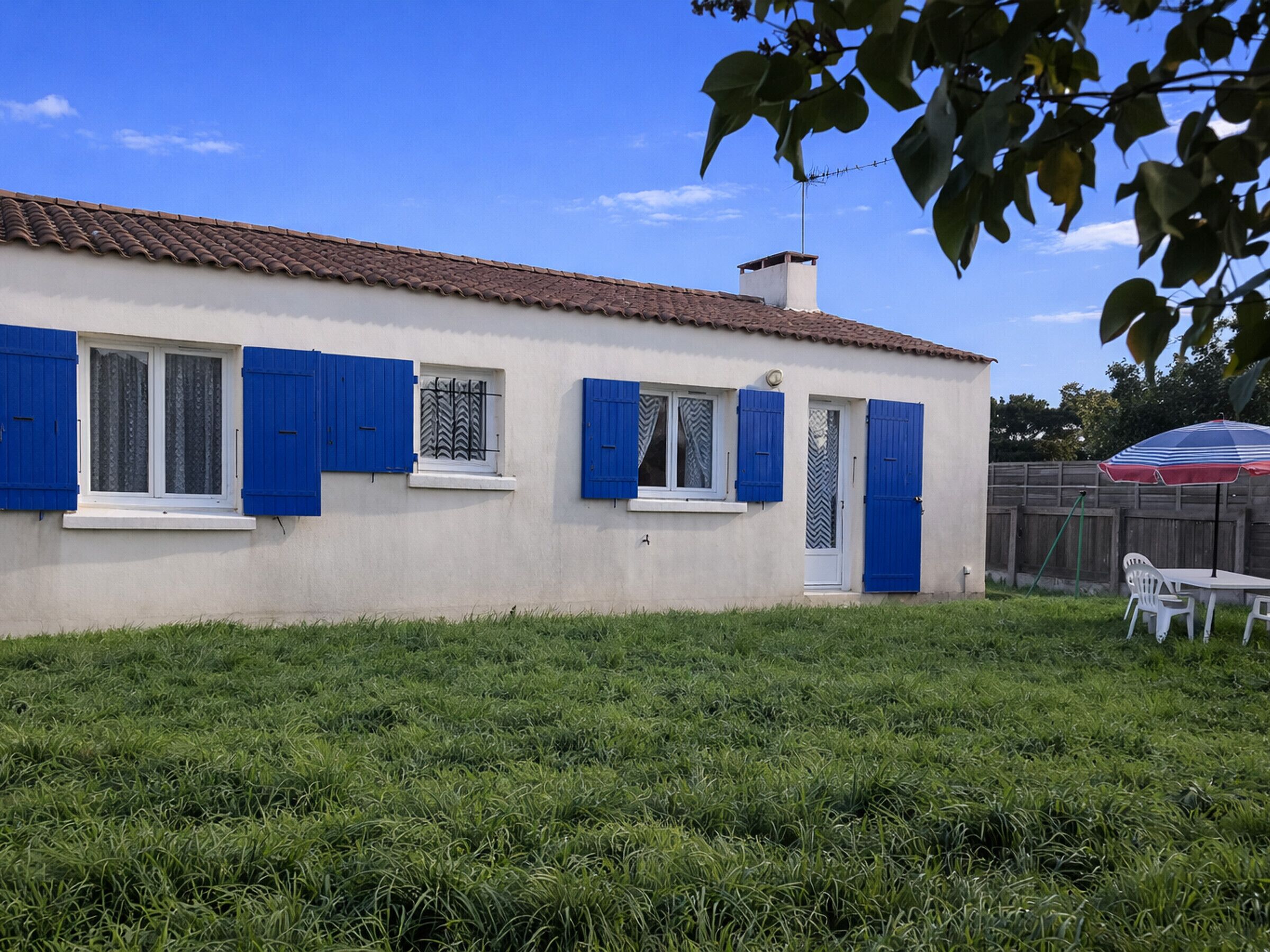 A house with a tiled roof, blue shutters, and a white door.
