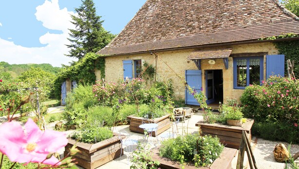 A rustic house with a sloped roof, wooden deck, and a garden with various plants and flowers. - Dordogne Valley, 4 * holiday house, exclusive pool, 12kms from Bergerac (Bergerac)