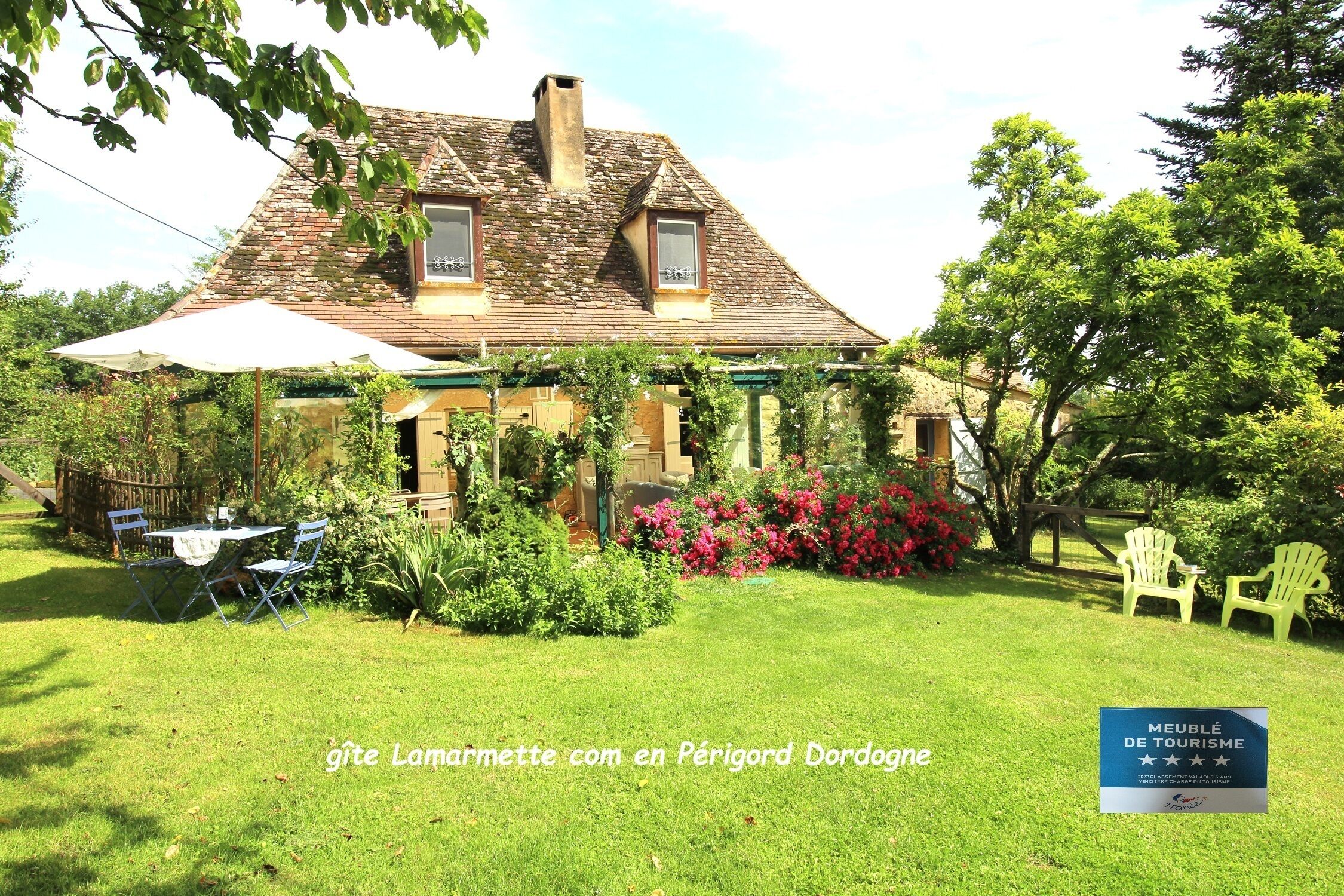 Een traditioneel huis met een tuin, buitenmeubilair en een bord dat het als toeristenverblijf identificeert.