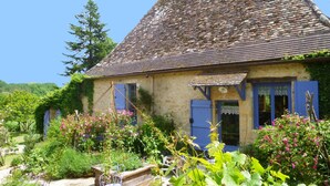 A rustic stone house with a sloped roof, surrounded by lush greenery and flowering plants. - Dordogne Valley, 4 * holiday house, exclusive pool, 12kms from Bergerac (Bergerac)