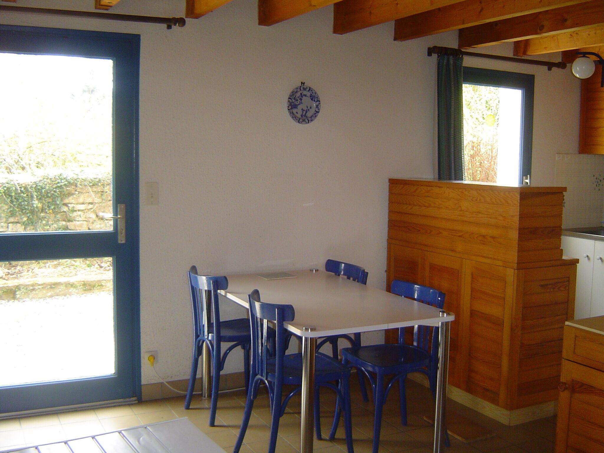A dining area with a table and chairs, a wooden cabinet, and a window with a view of greenery.
