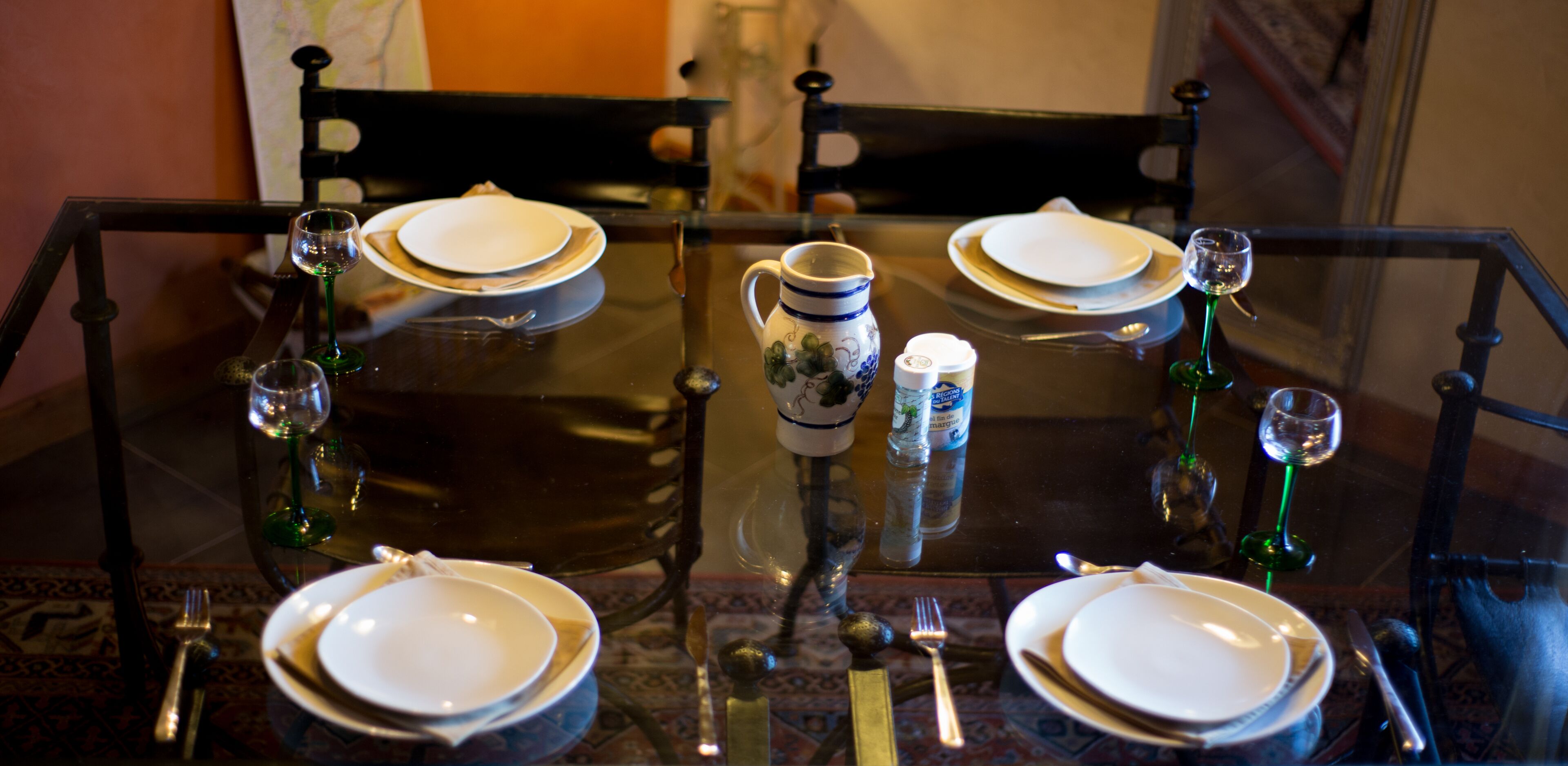 A dining table set for four with plates, cutlery, and glasses.