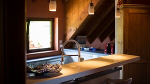 A kitchen with a wooden ceiling, a sink with a modern faucet, and pendant lights.