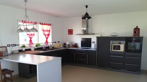A modern kitchen with a central island, dark cabinetry, and a microwave.