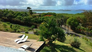 Un resort con zona de piscina, sillones de descanso y vistas al mar y a las montañas.