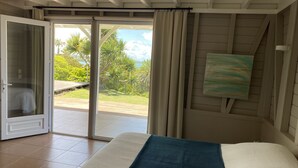 Un dormitorio con cama, puerta corrediza de vidrio que da a un balcón y un cuadro en la pared.