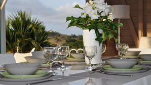 Mesa lista para comer con un jarrón de flores blancas, vasos transparentes y platos.