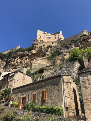A historic stone building with a steep, rocky hill behind it. - Charming cottage and nature, 18 ha, Périgord Noir-Dordogne -Lot -PISCINE and private SPA (Orliaguet)